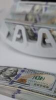 A wad of USD dollars is on the table. One hundred dollar bills are counted in the money machine. Blurred background. Vertical video