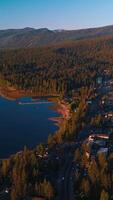 Stunning scenery of beautiful Lake Tahoe on sunny warm day. Waterfront with all the necessary infrastructure and blue water of lake with numerous boats. Top view. Vertical video