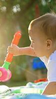 Beautiful baby boy playing with a toy hammer. Little toddler kid spending time outdoors in the rays of setting sun. Vertical video