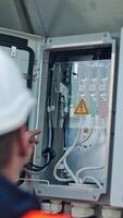 Electrician checks the wires of electric system. Male engineer controls the operation of the power system on a transformer. Vertical video