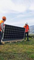 New solar panels on the grass. Workers installing photovoltaic panels for renewable energy. Construction of solar panels for new source of electricity. Vertical video