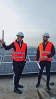 Solar panels installation. Workers are talking about innovative technologies on the modern photovoltaic farm. New source of energy. Vertical video