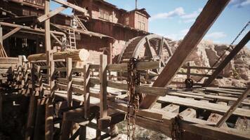 A rustic wooden bridge with a waterwheel in a mining town under clear skies video