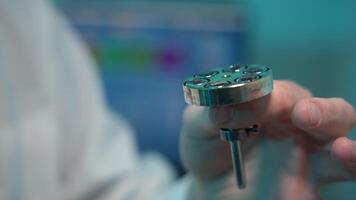 Close-up of scientist holding detail. Stock footage. Chemist or physicist holds steel part for device in hand. Scientist gives part physical properties during experiment video