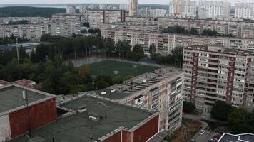 Aerial view of old sleeping area with highrise buildings, green trees, and football field. Stock footage. Summer cityscape. video