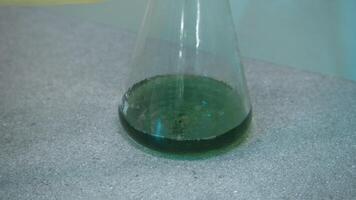 Working with chemical elements. Stock footage. Green medicine in test tubes with working scientists in a specially isolated room. video