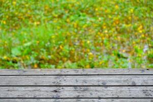 Wooden floor with lotus pond as background, green grass.Green background image photo