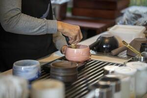 Woman whisking matcha powder while making matcha green tea with traditional accessories for tea ceremony photo