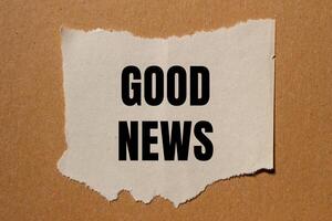 Good news message written on ripped torn paper piece with brown background. Conceptual good news symbol. Copy space. photo