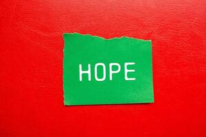 Hope message written on ripped torn green paper piece with red background. Conceptual hope symbol. Copy space. photo