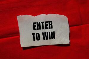 Enter to win message written on ripped torn paper piece on red background. Conceptual enter to win symbol. Copy space. photo