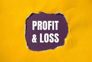 Profit and loss message written on ripped torn yellow paper with purple background. Conceptual profit and loss symbol. Copy space. photo