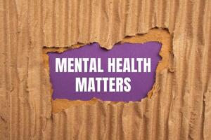 Mental health matters message written on ripped torn cardboard paper with purple background. Conceptual mental health matters symbol. Copy space. photo