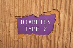 Diabetes type 2 message written on ripped torn cardboard paper with purple background. Conceptual diabetes type 2 symbol. Copy space. photo