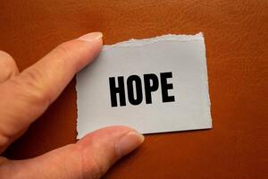 Hope message written on ripped torn paper piece with brown background. Conceptual hope symbol. Copy space. photo