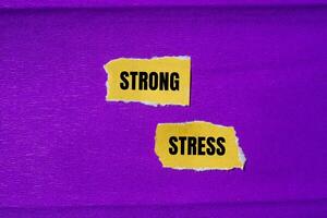 Strong stress message written on ripped torn yellow paper pieces with purple background. Conceptual strong stress symbol. Copy space. photo