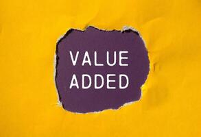 Value added message written on ripped torn yellow paper with purple background. Conceptual value added symbol. Copy space. photo