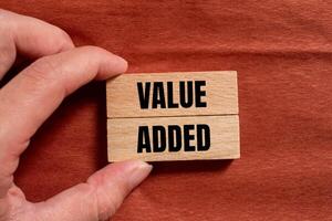 Value added message written on wooden blocks with brown background. Conceptual value added symbol. Copy space. photo