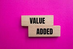 Value added message written on wooden blocks with pink background. Conceptual value added symbol. Copy space. photo