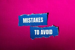 Mistakes to avoid message written on ripped torn blue paper pieces with pink background. Conceptual mistakes to avoid symbol. Copy space. photo