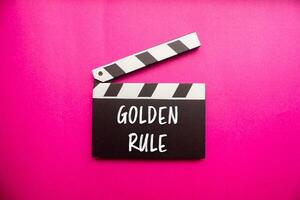 Golden rule message written on clapperboard with pink background. Conceptual golden rule symbol. Copy space. photo