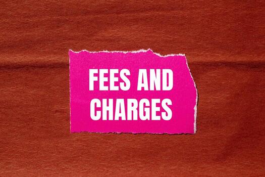 Fees and charges message written on ripped pink torn paper piece with brown background. Conceptual fees and charges symbol. Copy space. photo