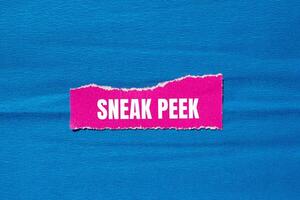 Sneak peek message written on ripped torn pink paper piece with blue background. Conceptual sneak peek symbol. Copy space. photo