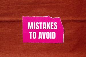 Mistakes to avoid message written on ripped pink torn paper piece with brown background. Conceptual mistakes to avoid symbol. Copy space. photo