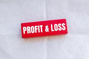Profit and loss message written on red wooden block with white background. Conceptual profit and loss symbol. Copy space. photo