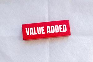 Value added message written on red wooden block with white background. Conceptual value added symbol. Copy space. photo