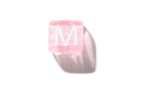 Pink transparent cube with white letter m isolated on clean white background with shadow photo