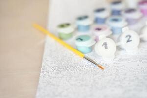 Paint by numbers kit on canvas with brush and colorful paint pots for creative artistic relaxation and mindfulness. photo