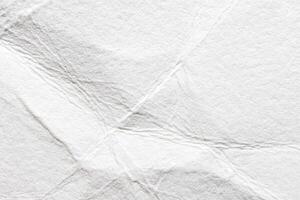 Close-up of crumpled white paper texture with wrinkles and folds for creative background designs. photo