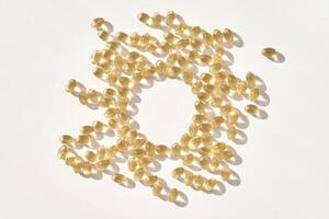 Vitamin d capsules arranged in circle on white surface with shadows and light reflection photo