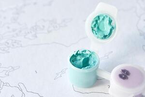 Close-up of blue paint in plastic containers on a paint-by-numbers canvas for creative art projects. photo