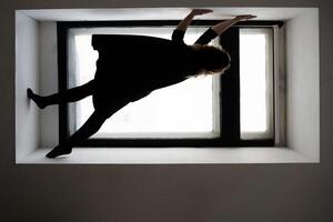 Creative indoor photography. silhouette of a woman balancing gracefully on window ledge in minimalist setting. photo