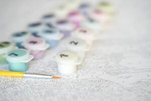 Paint by numbers kit with brush and color pots for relaxing creative art activity on detailed canvas. photo