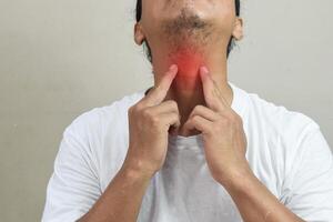 Inflammation of the thyroid gland, sore throat and cough, man with neck pain on grey background. Health problems concept photo