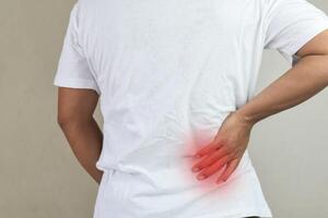 Man standing with hand touching her back having back pain photo