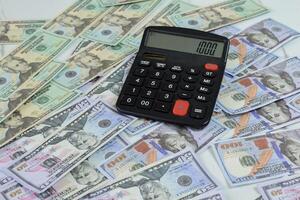 Calculator and a collection of dollar banknotes on the table, financial management concept photo