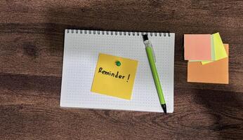 Concept of Reminder write on sticky notes isolated on Wooden Table. photo