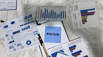 Concept of Assessor write on sticky notes isolated on Wooden Table. photo