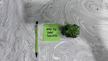 Concept of Key to SME Success write on sticky notes isolated on Wooden Table. photo