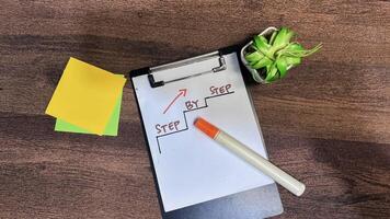 Concept of Step by Step write on paperwork isolated on wooden background. photo