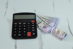 Roll of Dollar banknotes and calculator on the table photo