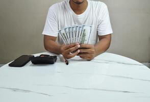 Businessman's hand holding one hundred dollar bill, investment and finance in mobile applications, trading on mobile phone. photo