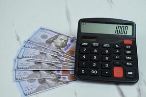 One hundred dollar and calculator on the table, financial management concept photo