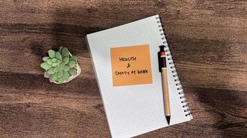 Concept of Health and Safety at Work write on sticky notes isolated on Wooden Table. photo