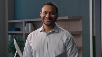 Business portrait in office adult Indian man American guy ethnic businessman entrepreneur employer with laptop posing at workplace modern marketing company manager holding computer smiling at camera photo