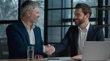 Close-up unrecognizable Caucasian men businessmen business partners employees sign contract document paperwork shaking hands successful partnership deal cooperation agreement handshake in sunny office photo